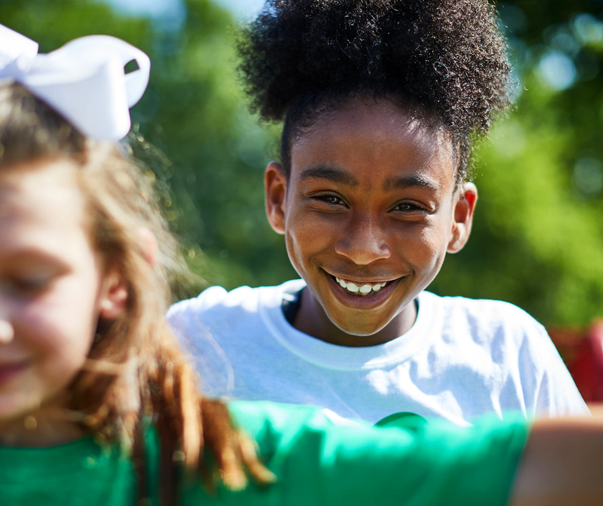 Two children playing.  Focus is on smiling child in back. 