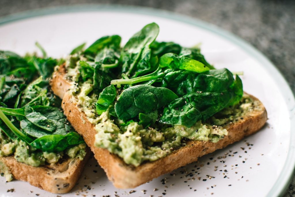 Piece of toast with spinach and spread on plate. 