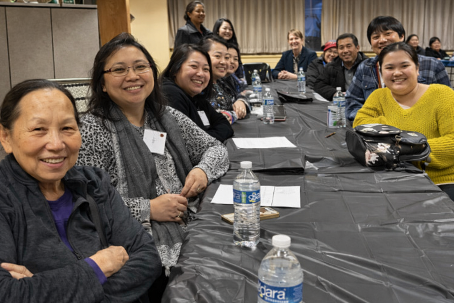 Hmong growers sitting at a conference table smiling.