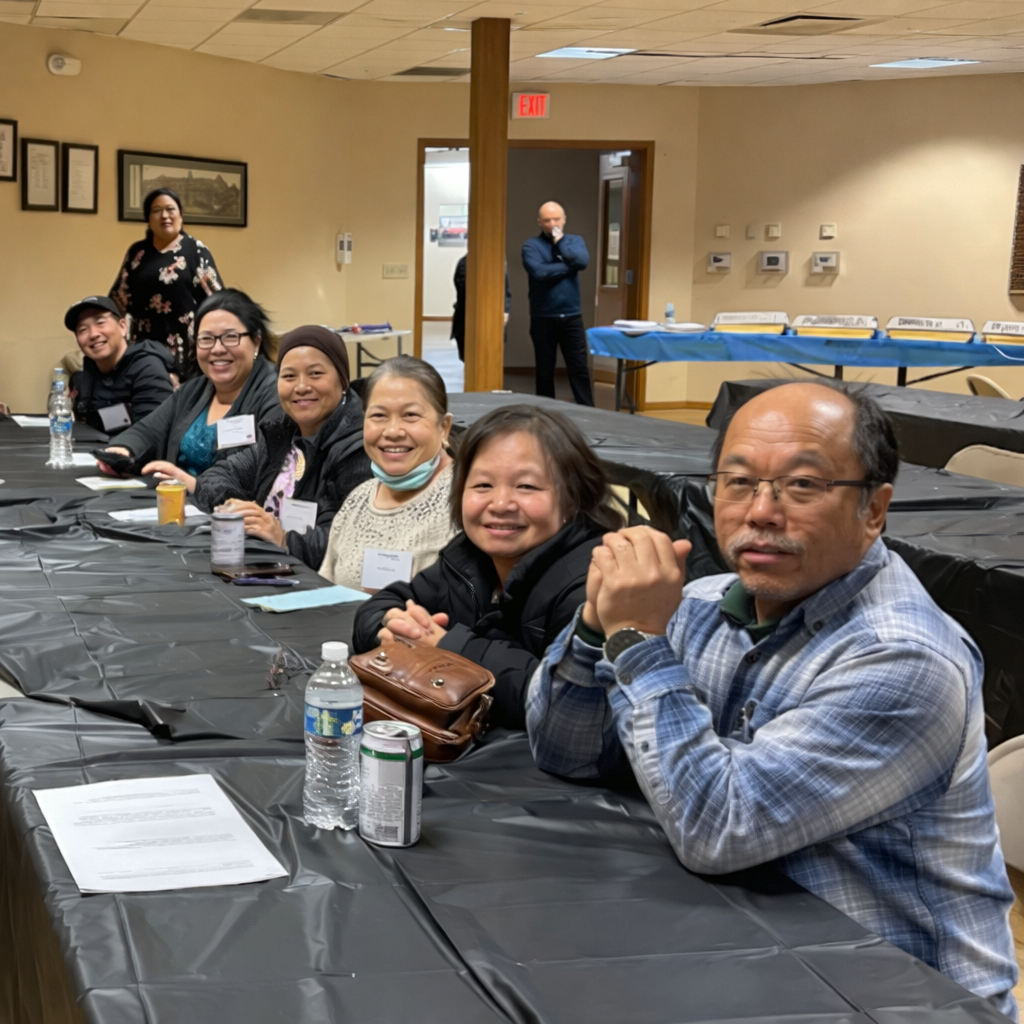 Hmong growers sitting at conference tables smiling.